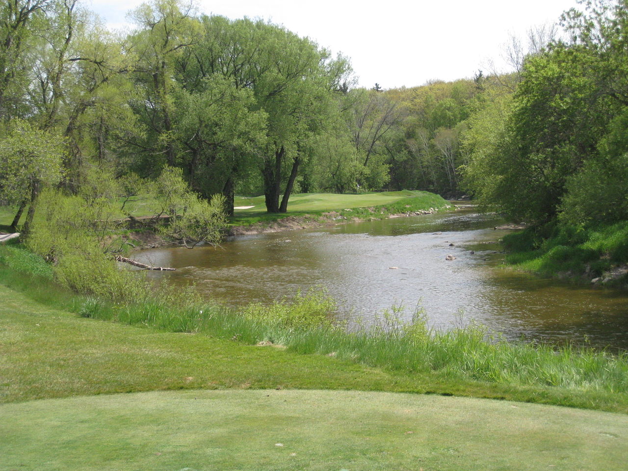 The 13th tee shot at the River Course at Blackwolf Run, over the Sheboygan River to a tree-lined green, in Kohler, Wisconsin
