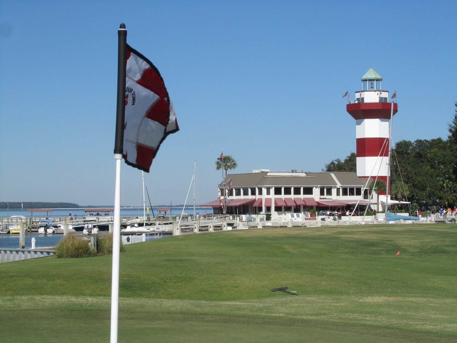 The 18th green at Harbour Town Golf Links with the red-and-white Harbour Town Lighthouse and the marina behind it, on Hilton Head Island, South Carolina