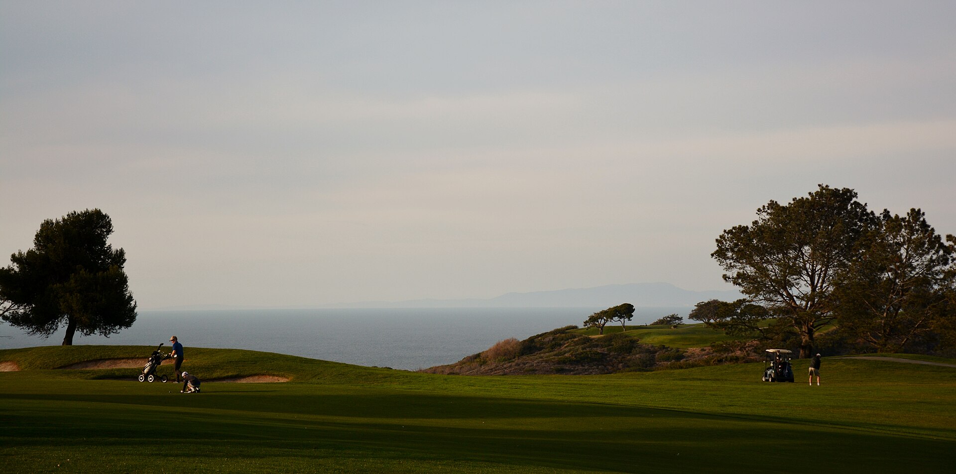 The cliff-top holes of the South Course at Torrey Pines, with striped fairways, Torrey pines and the Pacific Ocean behind, in La Jolla, California